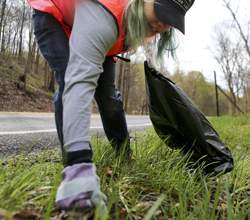 Lincoln Griffin, a volunteer with the Rachel Carson Trails Conservancy, picks up trash from the roadside along a portion of the trail named for ecologist author Rachel Carson.